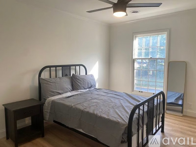 A bedroom with a bed, nightstand, and window.