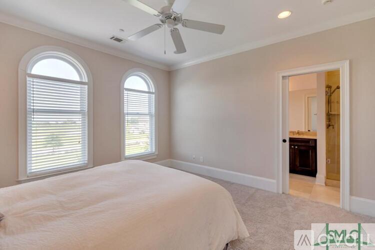 A bedroom with a large bed and a ceiling fan.