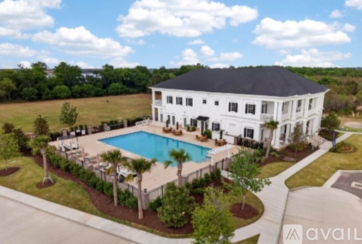 A large white house with a black roof and a pool in the backyard.