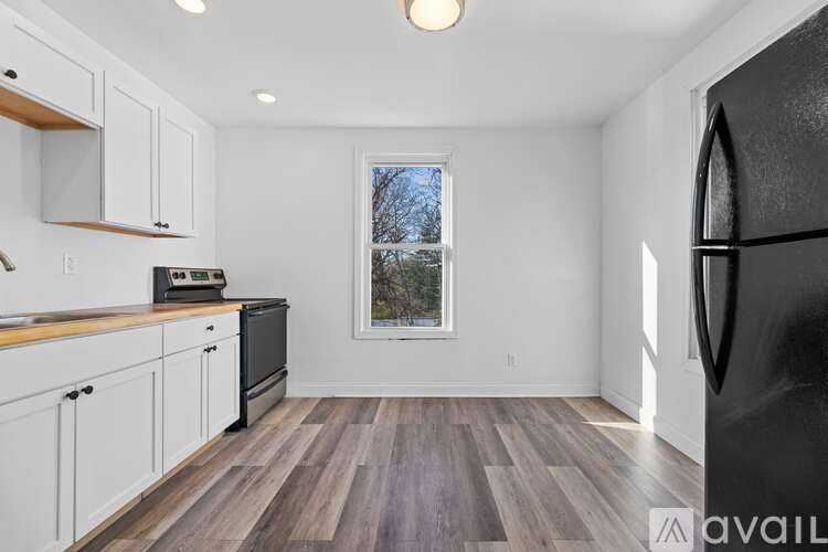 A kitchen with white cabinets and a black fridge.