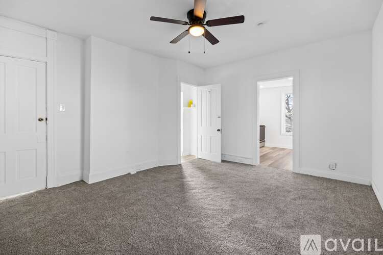 A spacious room with a ceiling fan and carpeted floor.