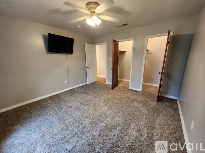 A living room with a flat screen TV mounted on the wall and a carpeted floor.