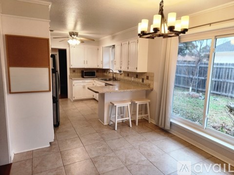 A kitchen with white cabinets and a black refrigerator.