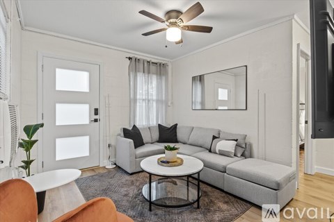 A living room with a grey sofa, a white coffee table, and a ceiling fan.