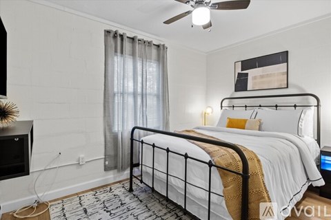 A bedroom with a bed, a ceiling fan, and a wall-mounted shelf.