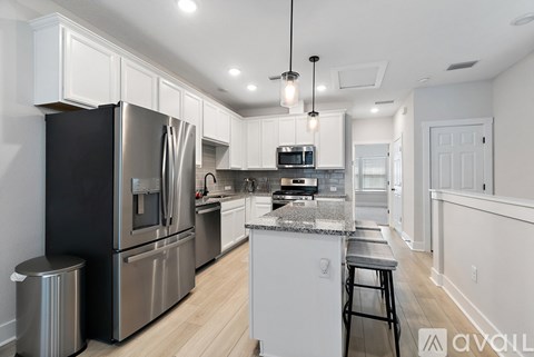A kitchen with a black refrigerator and white cabinets.
