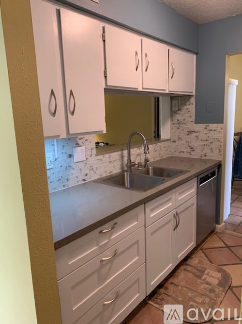 A kitchen with white cabinets and a marble backsplash.