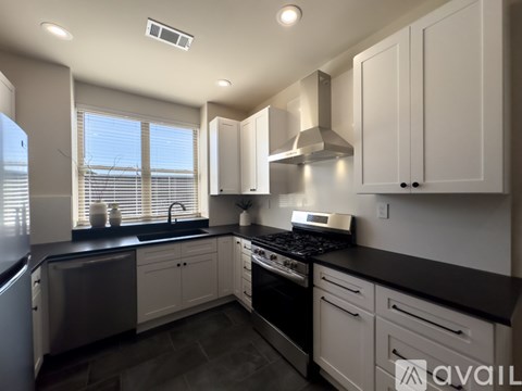 A modern kitchen with white cabinets and black countertops.