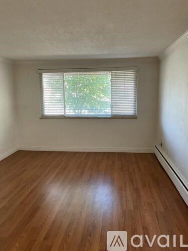 A room with wooden flooring and a window with blinds.