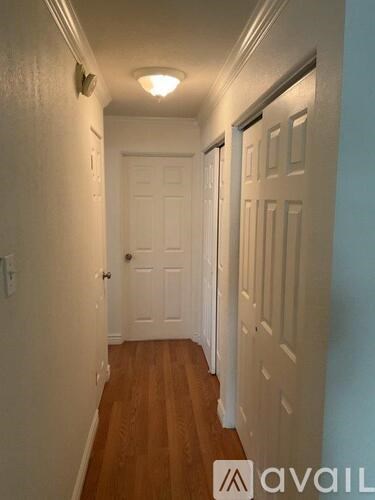 A hallway with a wooden floor and white walls.
