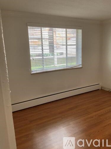 A room with wooden flooring and a window with blinds.