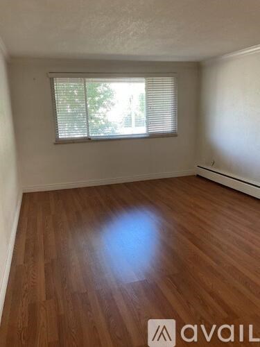 A room with wooden flooring and a window with blinds.