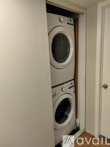 A washing machine is in a small space between a door and a wall.