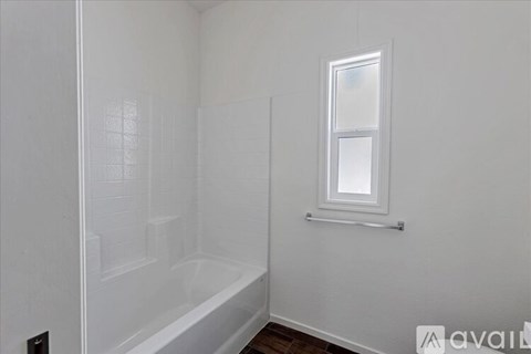A white bathroom with a tub and a window.