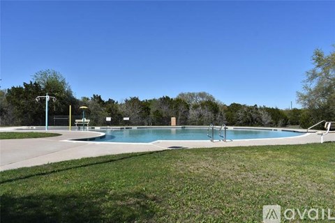 A large outdoor swimming pool surrounded by a grassy area and trees.