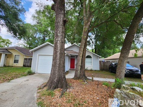 A house with a red door is surrounded by trees.