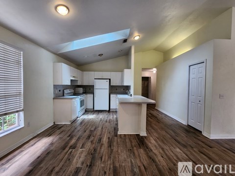 A kitchen with white appliances and a wooden floor.