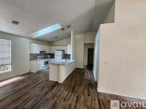 A kitchen with white appliances and wooden floors.