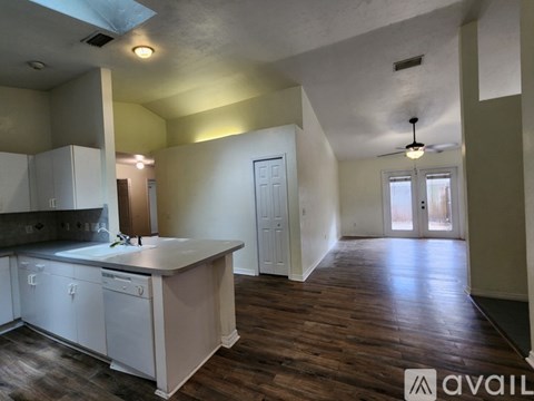 A kitchen with white cabinets and a wooden floor.