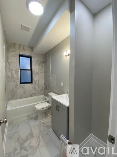 A bathroom with a marble patterned floor and a window.
