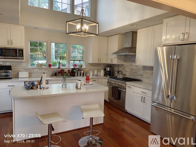 A kitchen with white cabinets and a stainless steel refrigerator.
