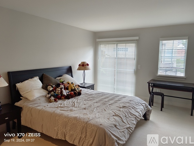 A bedroom with a bed, nightstand, and window with blinds.