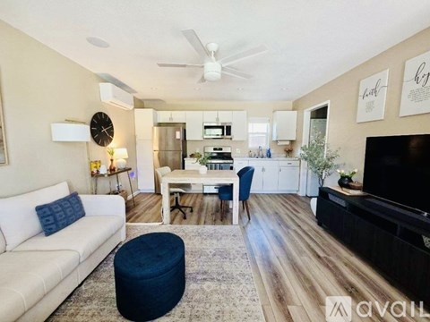 A living room with a white couch and a blue ottoman.