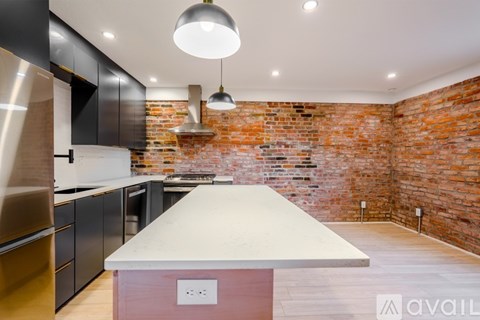 A kitchen with a large island in the middle and a brick wall behind it.