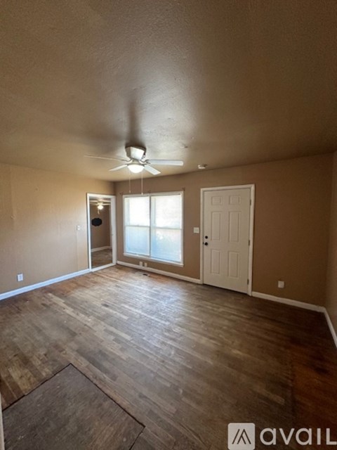 A room with a ceiling fan and wooden flooring.