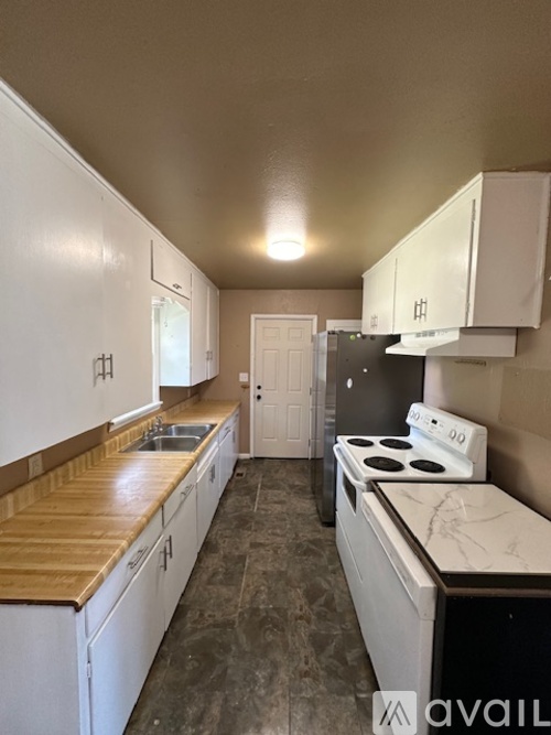 A kitchen with white cabinets and a wooden countertop.