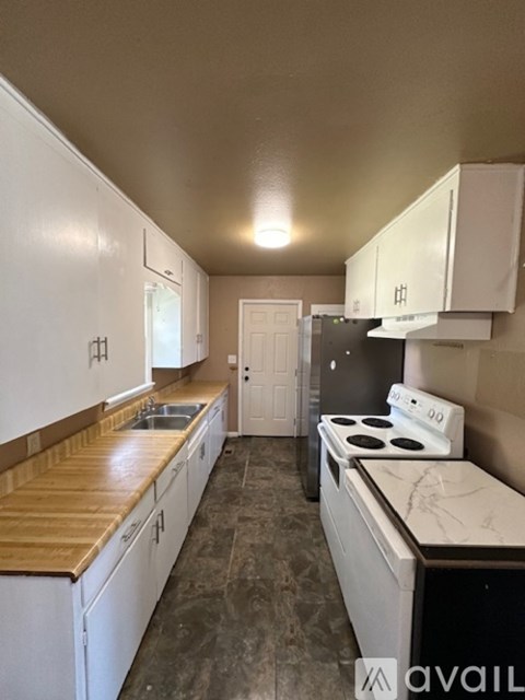 A kitchen with white cabinets and a wooden countertop.