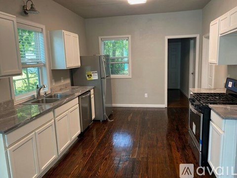 A kitchen with white cabinets and a wooden floor.