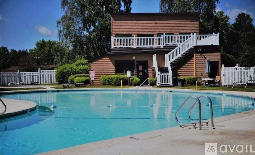 A large swimming pool in front of a house with a deck.