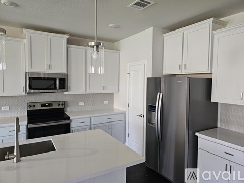 A kitchen with white cabinets and a stainless steel refrigerator.