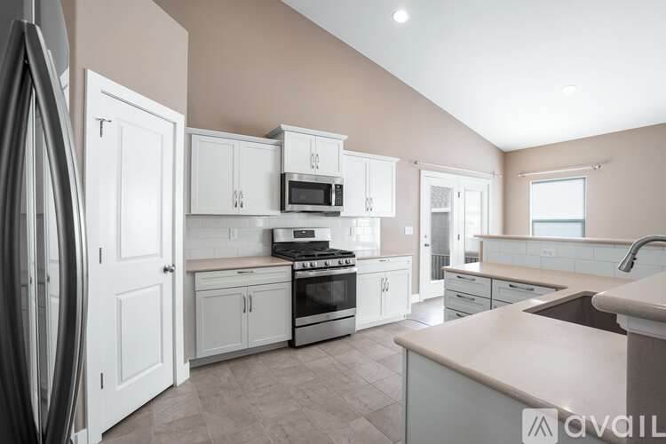 A kitchen with white cabinets and appliances, a countertop, and a window.