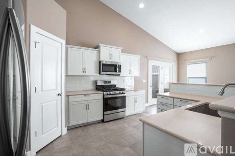 A kitchen with white cabinets and appliances, a countertop, and a window.