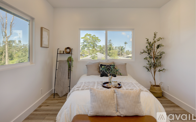 A bedroom with a large bed and a window overlooking trees.