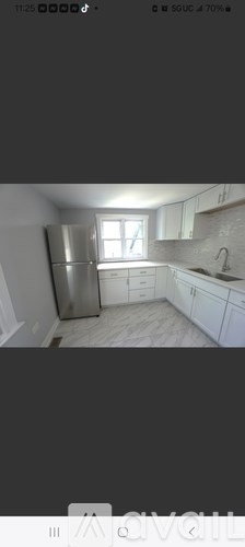 A kitchen with white cabinets and a stainless steel refrigerator.