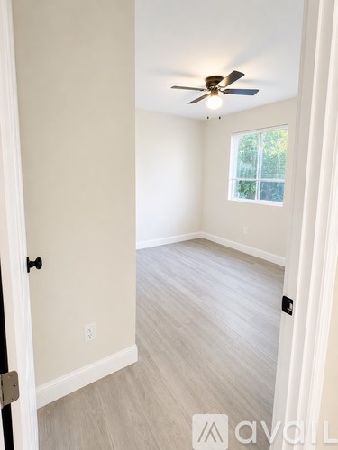 A room with a ceiling fan and light, a door, and a window.
