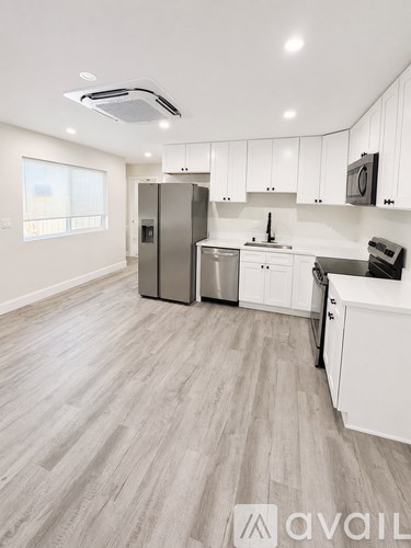 A kitchen with white cabinets and a wooden floor.