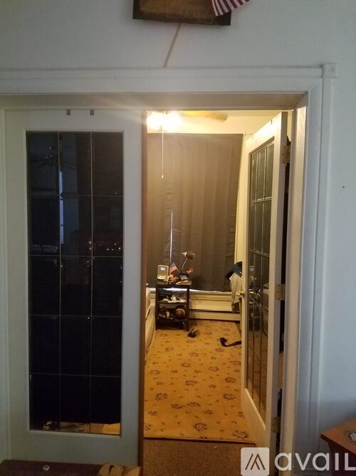 A room with a carpeted floor and a man sitting on a chair.