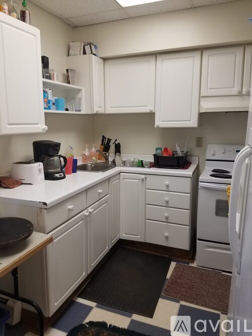 A kitchen with white cabinets and a black mat on the floor.