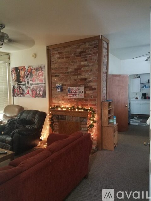 A living room with a red couch and a brick wall.