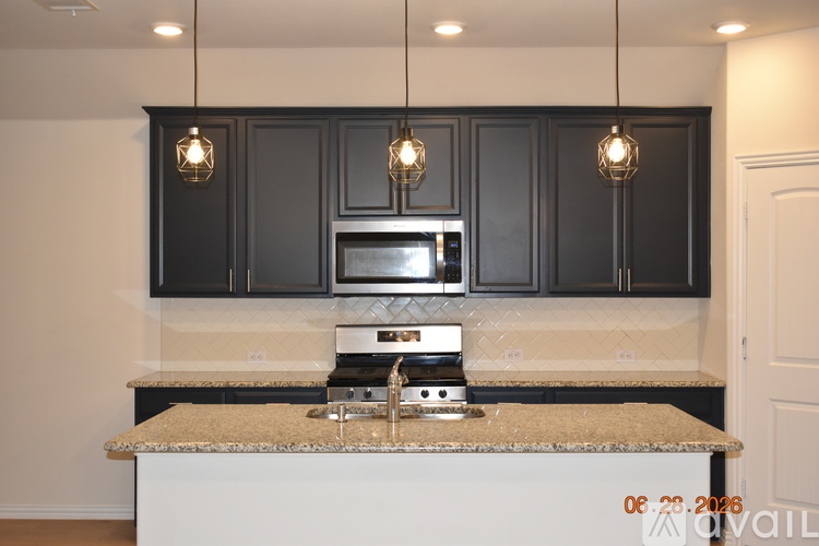 A kitchen with black cabinets and a granite countertop.
