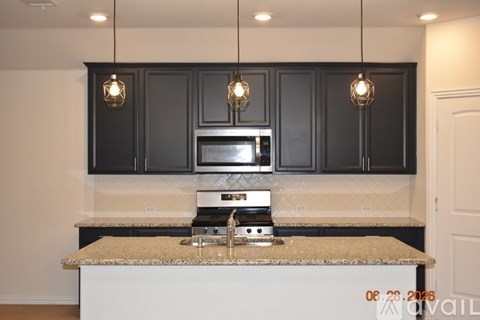 A kitchen with black cabinets and a granite countertop.