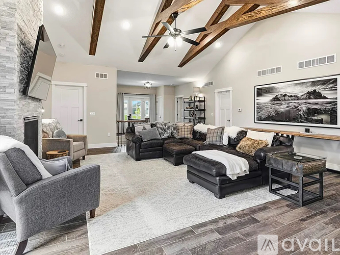 A spacious living room with a grey sofa and a black leather ottoman.
