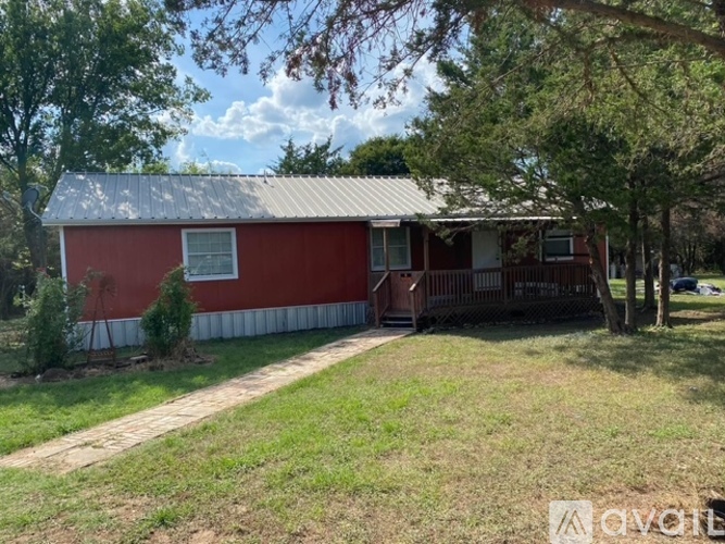 A red house with a porch and a tree in front.