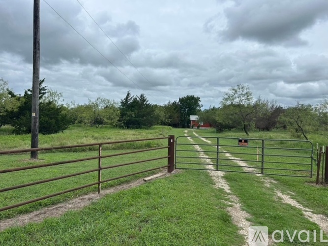A gate leads to a field with a cloudy sky overhead.