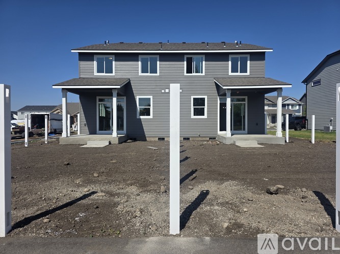 A grey house with a white door and windows is available for purchase.