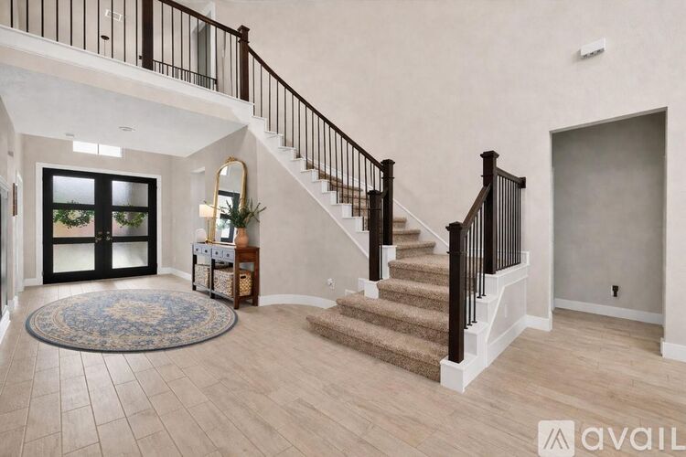 A spacious foyer with a staircase and a rug.